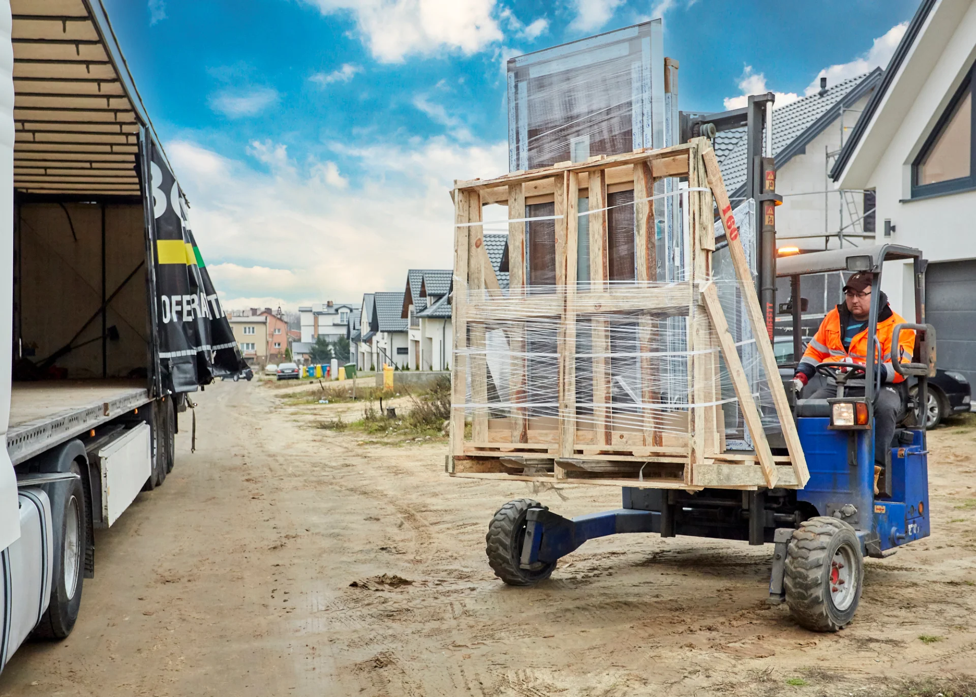Der grüne Gabelstapler verlädt ein gepacktes Set Fenster auf den LKW zur Auslieferung.